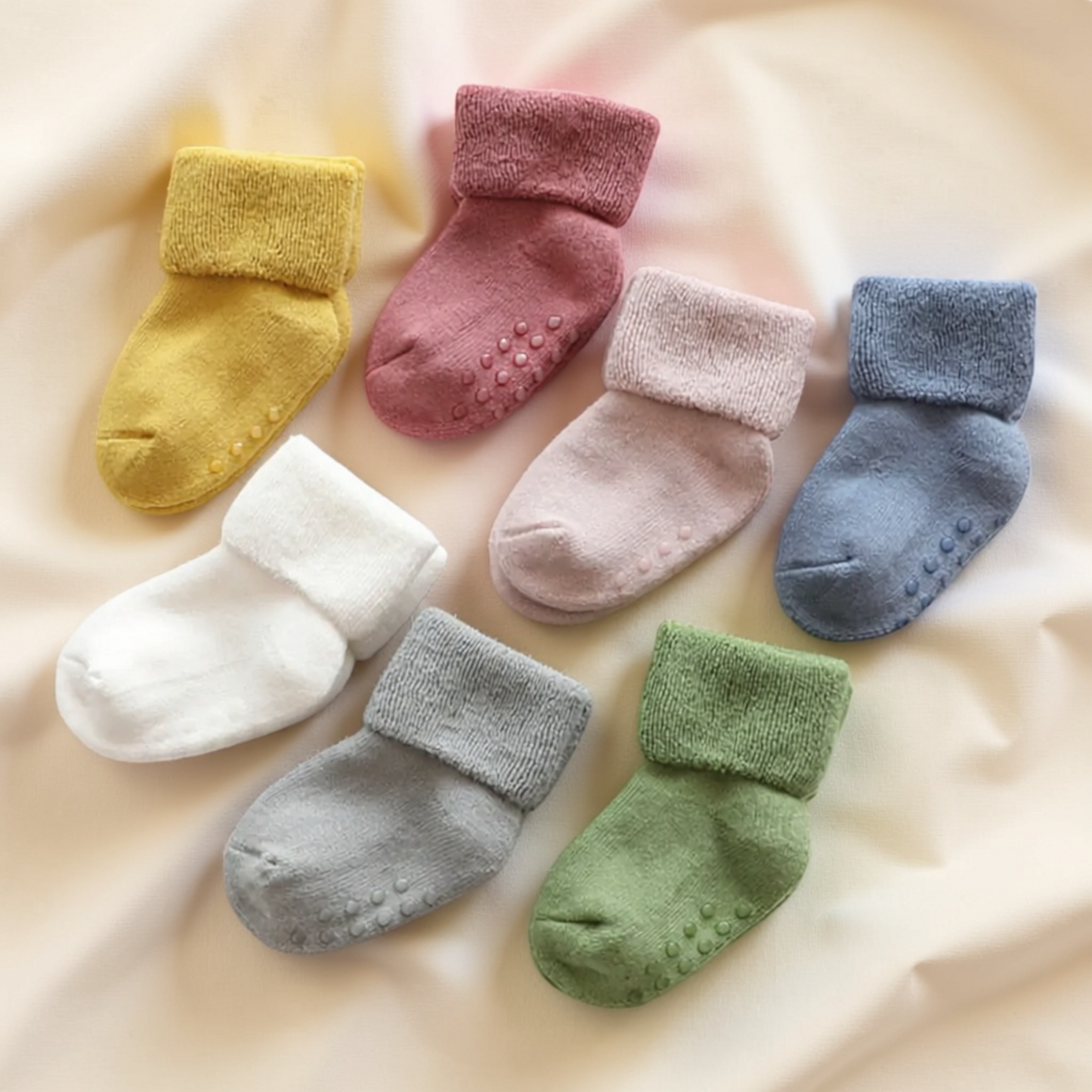 A collection of colorful baby socks arranged on a soft, light-colored fabric.